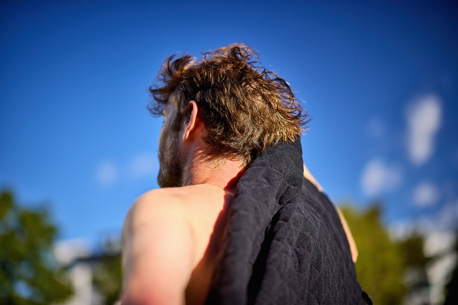 Person with a one440 towel over their shoulder against a blue sky