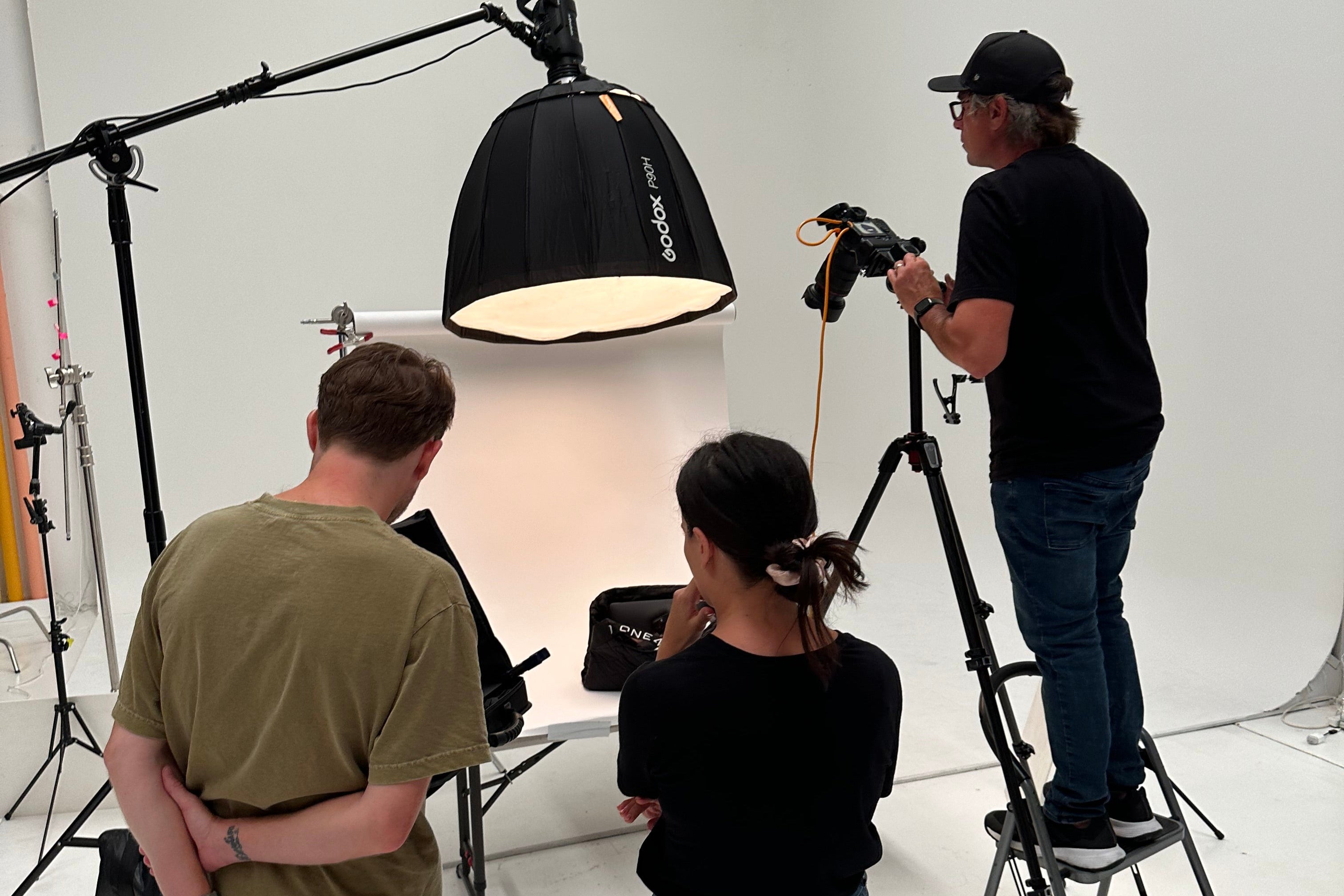 Film crew in a studio setting with lighting equipment and camera.