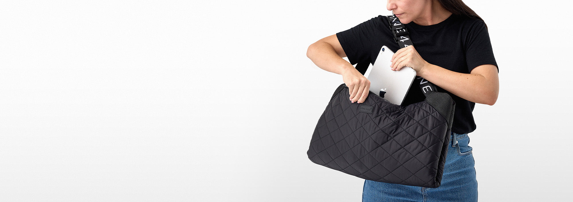Person holding a black quilted one440 handbag on a white background